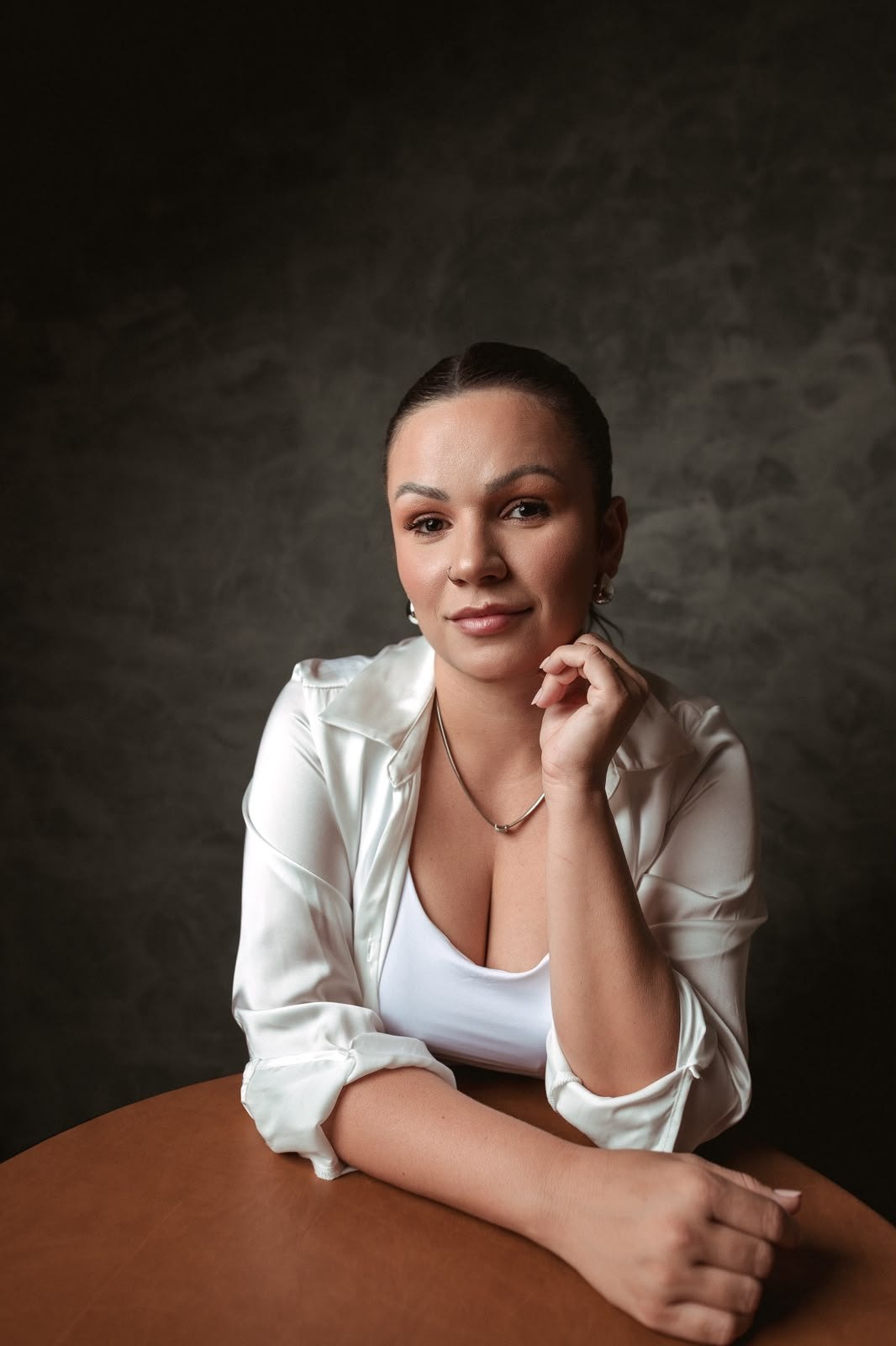 Layane Dola em retrato de estúdio, de camisa branca, olhando para a câmera